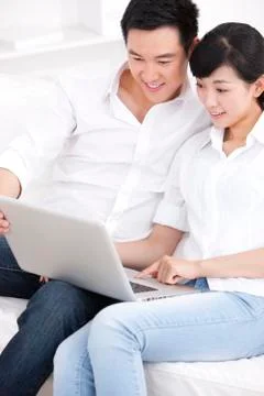 Young couple using laptop in sofa Stock Photos