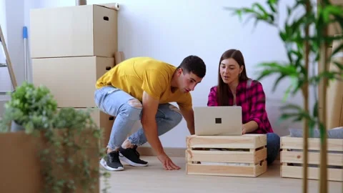 Young couple using laptop in their new home 스톡 동영상 244640864