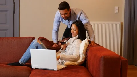A young couple using a laptop together in the living room Stock Footage 85692278