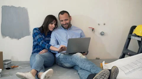 Young couple using laptop while sitting on floor at their new home Stock Footage 63993865