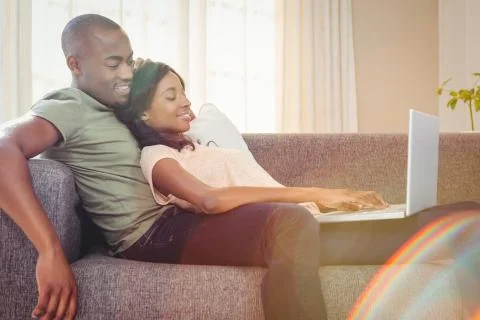 Young couple using a laptop while relaxing on a sofa in the living room 库存照片