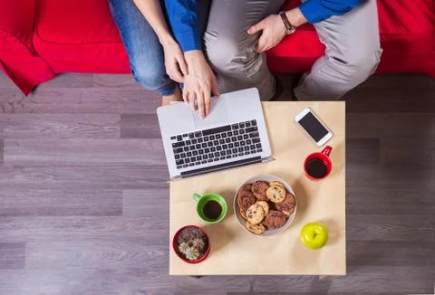 Young couple using laptop while sitting on couch Stock Photos