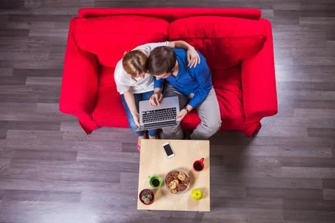 Young couple using laptop while sitting on couch Foto stock