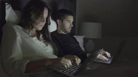 Young couple using laptops in bed Stock Footage 100548838