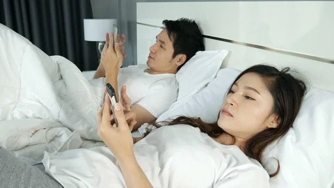 Young couple using mobile phone on bed in the bedroom Stock Footage 86334131