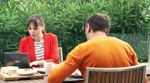 Young couple using modern laptop during breakfast on terrace at home  HD Stock Footage 57357268