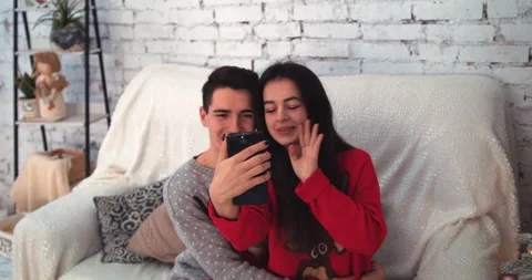 Young couple using smart phone talking to family congratulates Merry Christmas Stock Footage 144411307