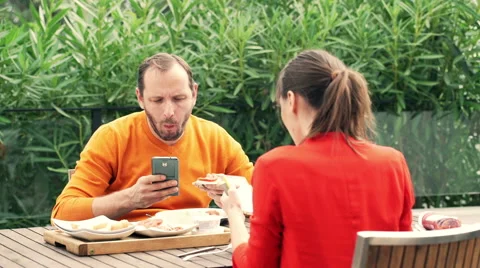 Young couple using smartphone during breakfast on terrace HD Stock Footage 57358363