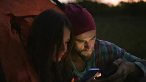 Young couple using a smartphone in the evening near the tent. Stock-Footage 116557029
