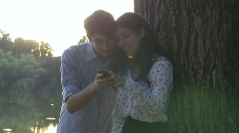Young couple using the smartphone in the park Stock Footage 64861205