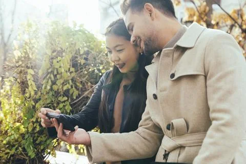 Young couple using smartphone together in the city street Stock Photos