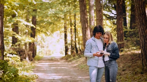 Young Couple Using Smartphone While Walks Through Forest Stock Footage 89893979