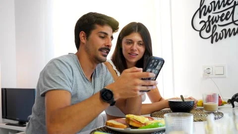 Young couple using smartphone while having breakfast at home Stock Footage 317145345