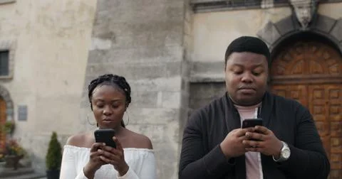 Young couple using smartphones while walking outdoors. Close up of busy couple Stock Photos