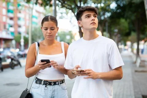 Young couple using smartphones while walking Fotos Stock