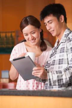 Young Couple Using Tablet in Kitchen Foto stock