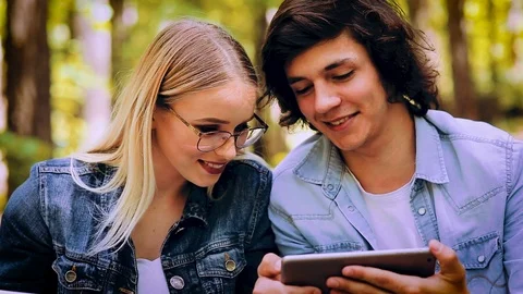 Young Couple Using Tablet While Sitting In Forest Stock Footage 89893273