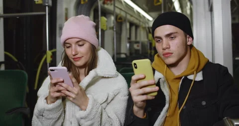 Young couple using their smartphones while sitting on seats in public transport Stock Footage 136829257