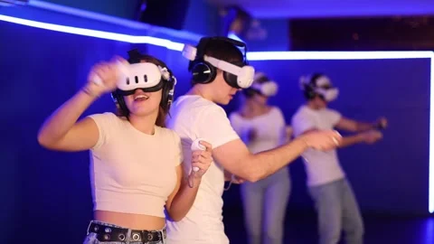 Young couple in VR glasses playing video game against another couple. Friends Stock Footage 344776021