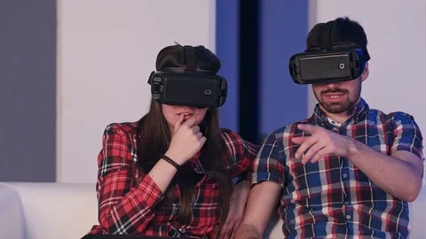 Young couple in vr headset watching movie sitting on a sofa Vídeo Stock 74389785