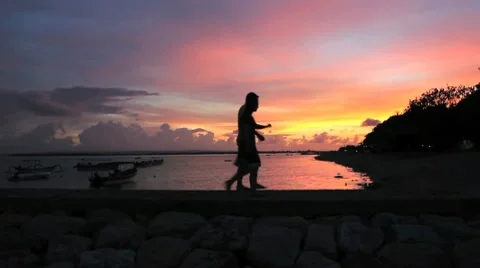 Young couple walking along a beach at sunset in silhouette Video stock 10607997