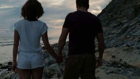 Young couple walking along coast in summer evening outdoor. Stock Footage 80267672