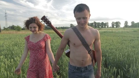 A young couple is walking along the wheat field. Video stock 78655108