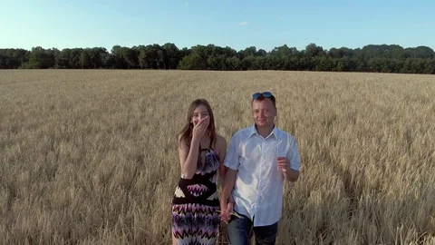 A young couple is walking along the wheat field,to the camera Stock Footage 89281710
