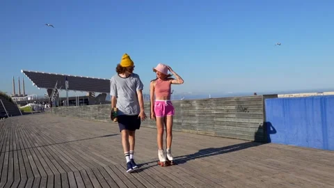 Young couple walking and roller skating on boardwalk Stock Footage 309984522