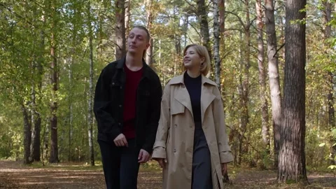 Young couple walking and talking in a forest during a sunny autumn day Stock Footage 314631780