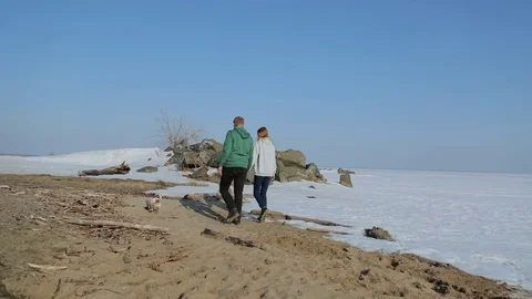 Young couple walking on the beach with the dog. spring beach with snow Vidéo 75006918