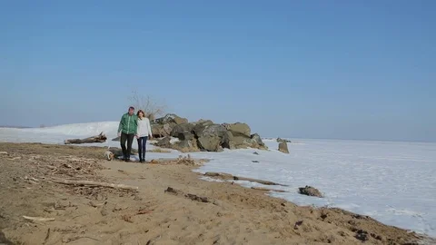 Young couple walking on the beach with the dog. spring beach with snow Vídeos de archivo 75007008