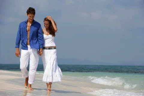 Young couple walking on beach Stock Photos