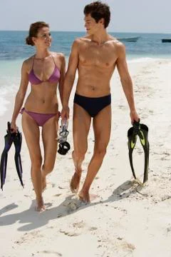Young couple walking up beach Stock Photos