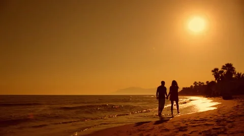 Young couple walking on beach in sunset Stock Footage 43618059