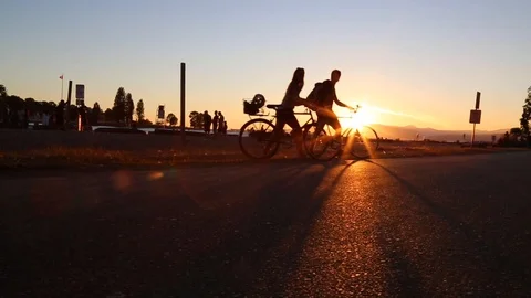 Young couple walking bicycles sunset beach lense flare Stock Footage 98570773