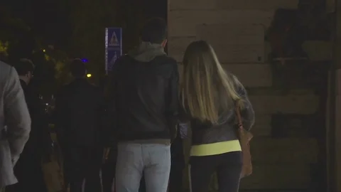 Young couple walking in crowd down street at night, night city life, slow-motion Stock Footage