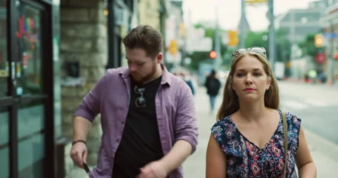 Young couple walking down a quiet street in a city, soft day lighting. Medium sh Stock Footage 199461763