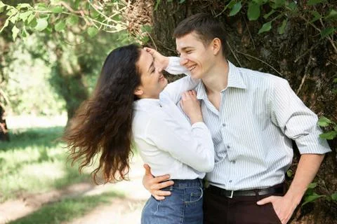 Young couple walking in the forest, posing near tree, summer nature, bright s Stock Photos