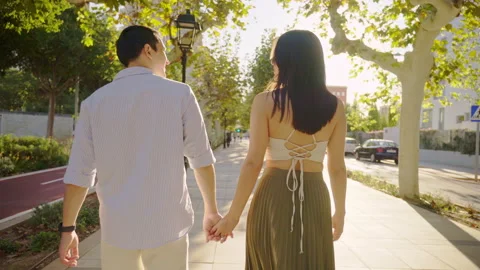 Young couple walking hand in hand on sunny city street Stock Footage 303854617