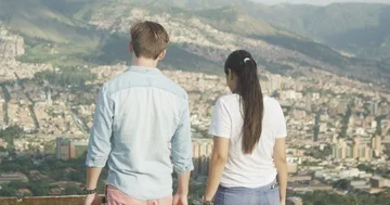 Young couple walking, talking and laughing in city park overlooking skyline Stock Footage 86150664
