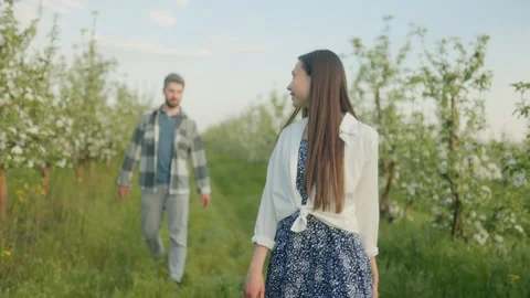 Young Couple Walking Through a Blooming Orchard on a Sunny Spring Day Stock Footage 307794979
