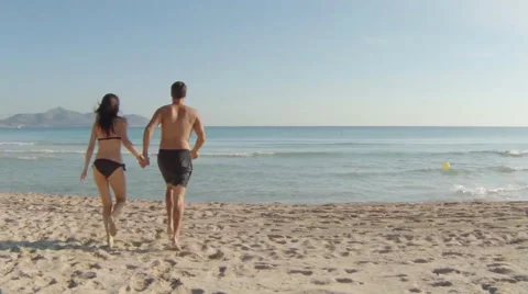 Young couple walking through shallow sea on the beach of majorca Vidéo 40909096