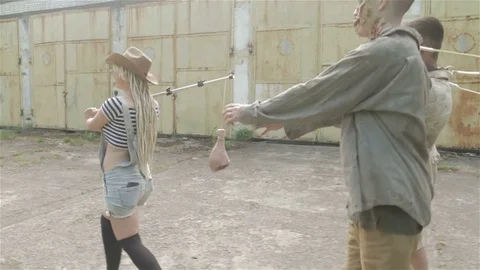 A young couple is walking with zombies on leashes. Slow motion. Stock Footage 77489444