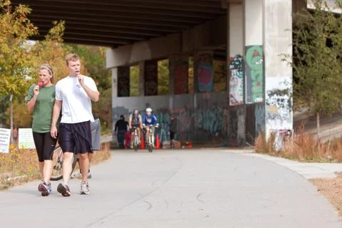 Young couple walks and eats popsicles in urban setting Stock Photos