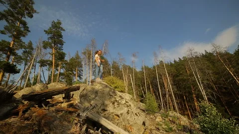 A young couple walks in a pine forest on stone rocks on a bright Sunny day. Stock Footage 96535660