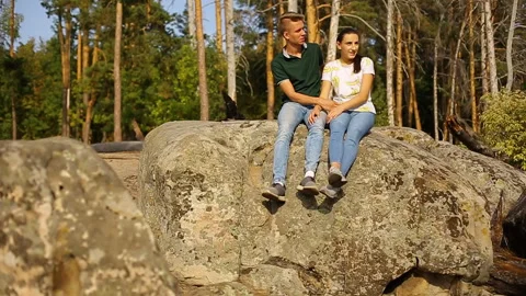 A young couple walks in a pine forest on stone rocks on a bright Sunny day. Stock Footage 97215013
