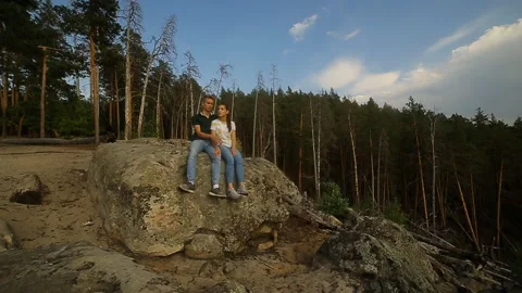A young couple walks in a pine forest on stone rocks on a bright Sunny day. Video stock 99012745