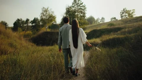Young couple walks through the hills in the field. Love concept. Free spirit in Vídeo Stock 320467807