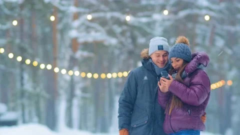 Young couple in warm jackets makes selfie in snowy city park Stock-Footage 133751387